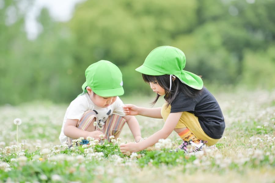 シロツメクサをつむ子どもたち